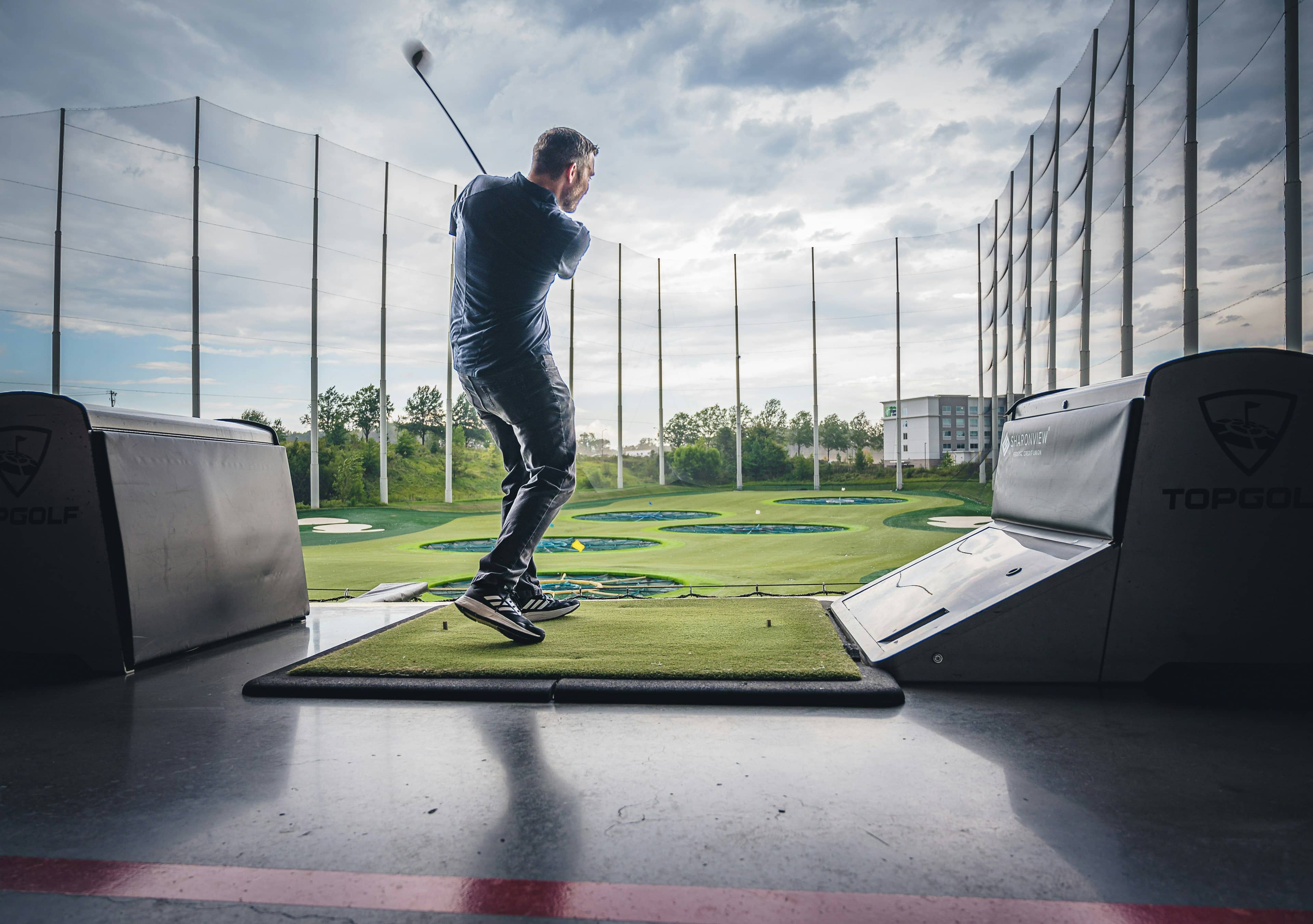 Golfer at a driving range reacting to a poor shot during a frustrating practice session.
