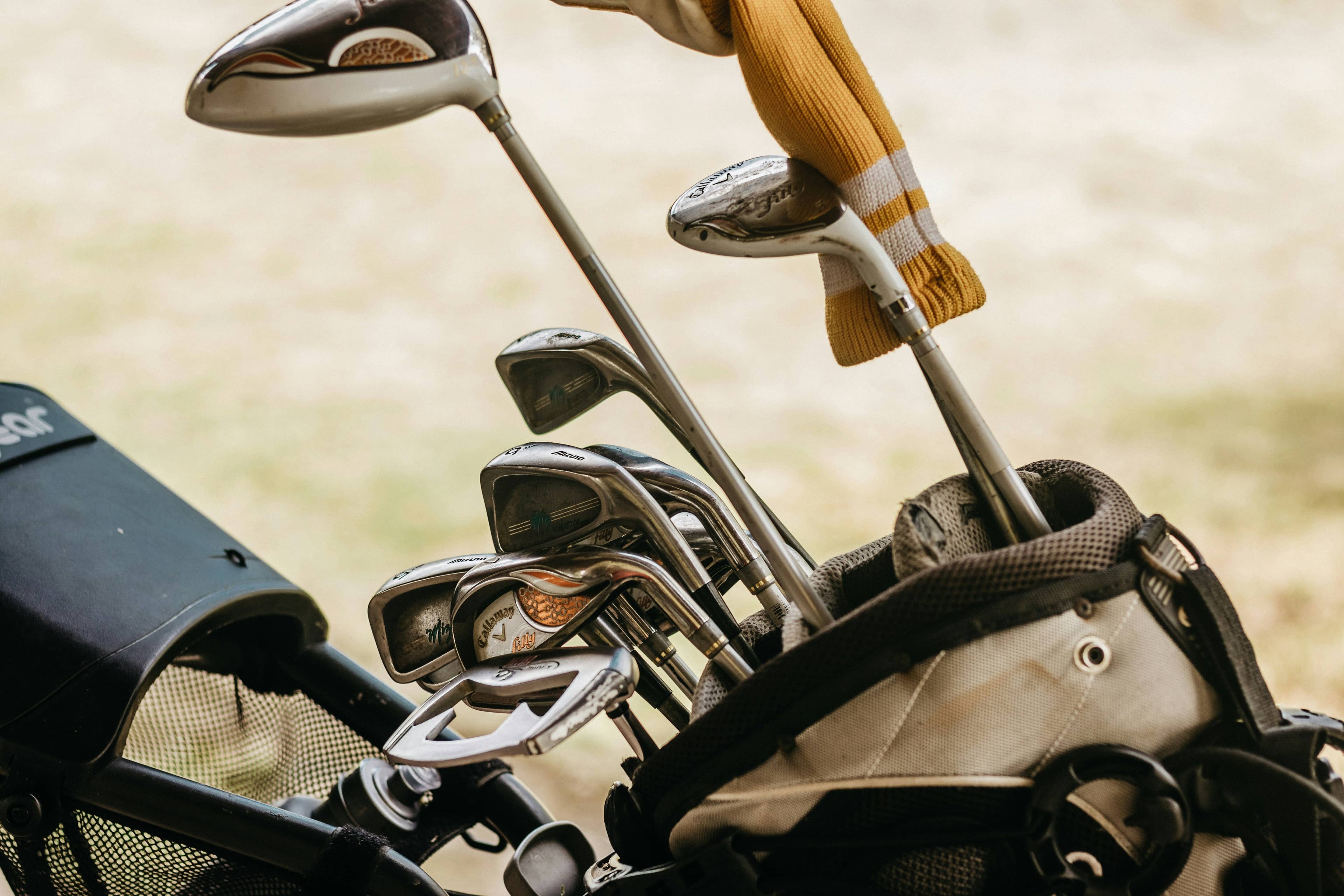 Old golf clubs standing in a golf bag, illustrating that beginners do not need new equipment before taking a golf lesson.