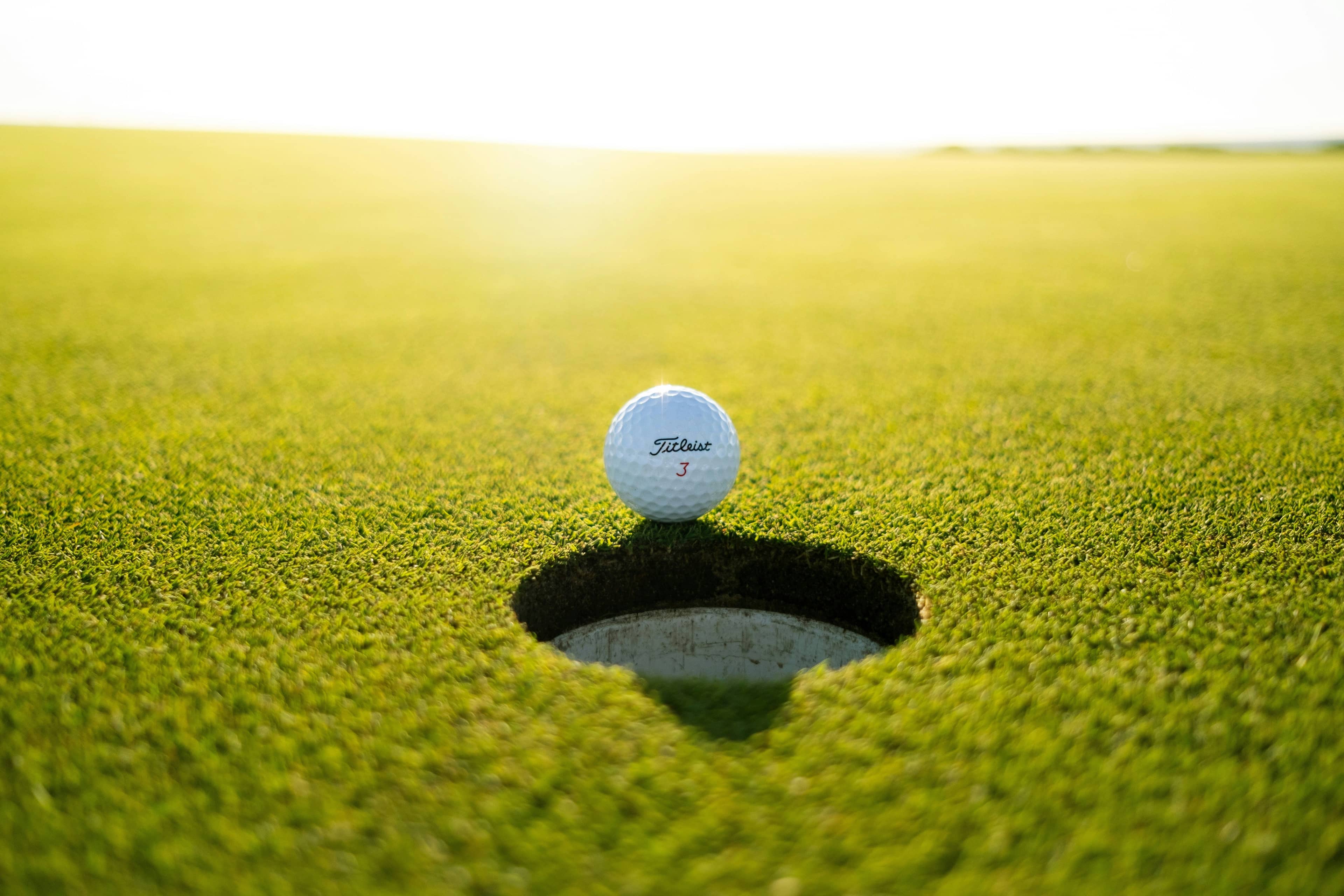 Golf ball rolls toward the hole on a putting green during a round.