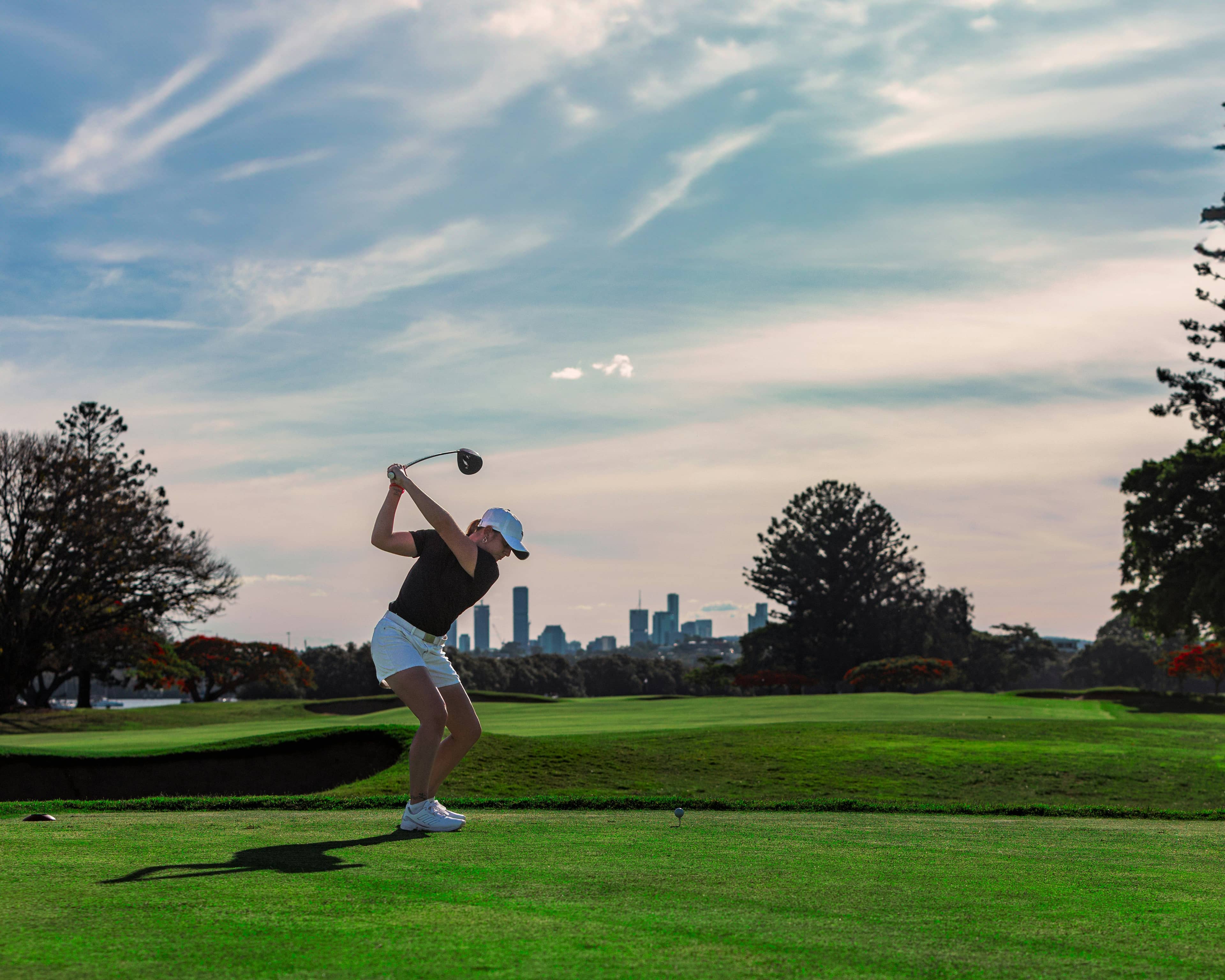 Woman golfer hitting a driver at the range with balanced posture and strong, controlled swing mechanics.