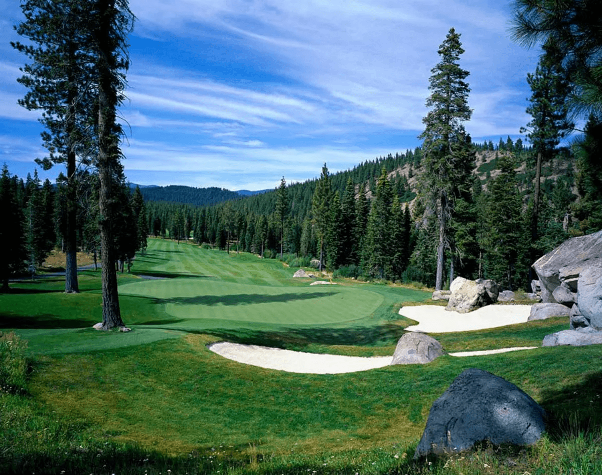 Coyote Moon Golf Course green with bunkers, granite boulders, and forested hills