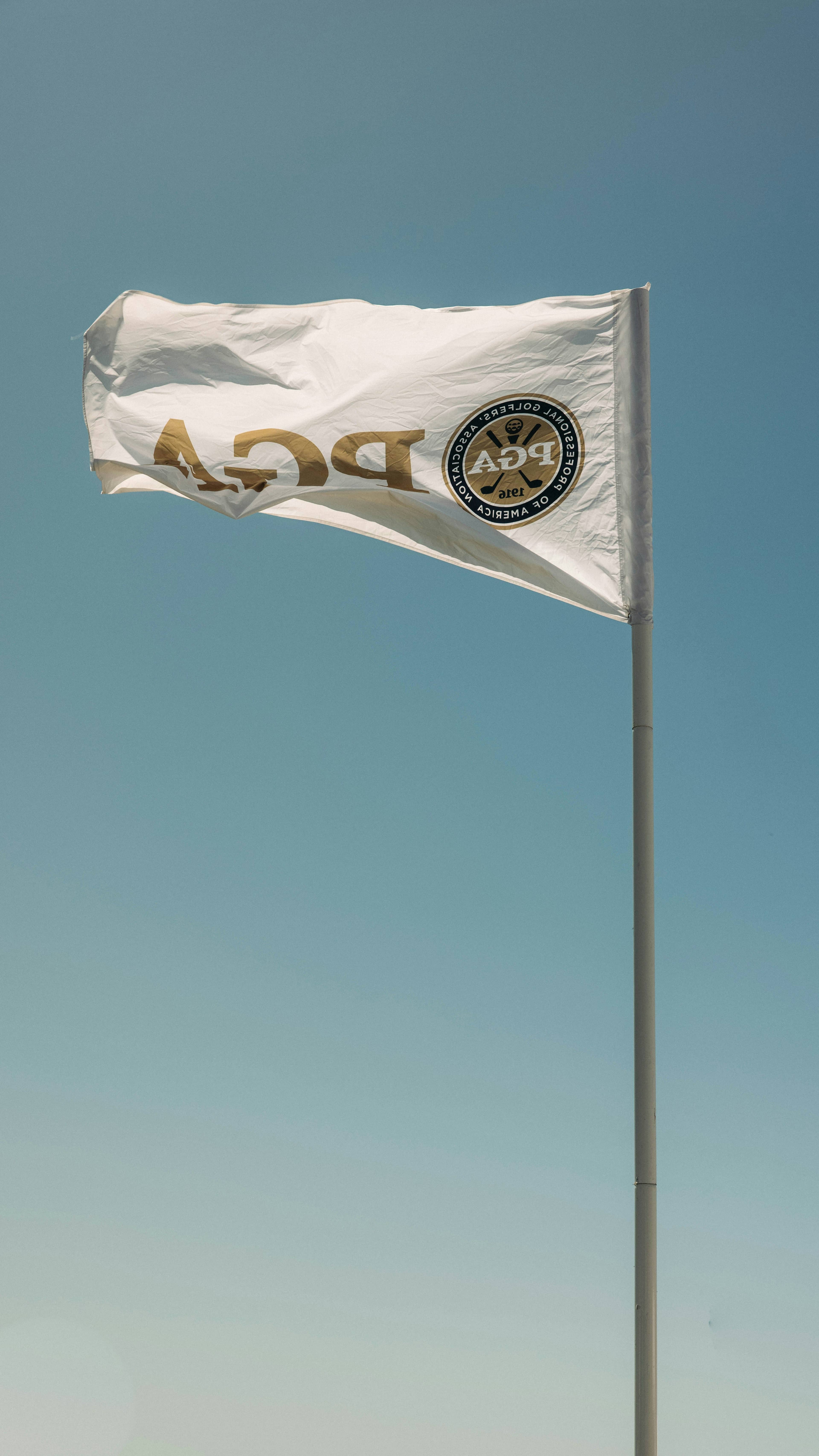 PGA flag on a golf course green, representing professional golf coaching credentials and certification.